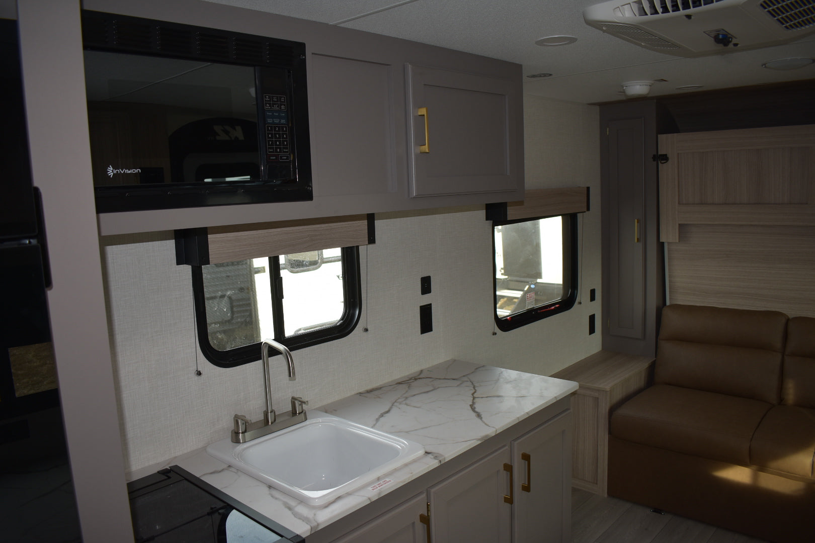 Interior of a compact living space with a sink, cabinets, and a couch.