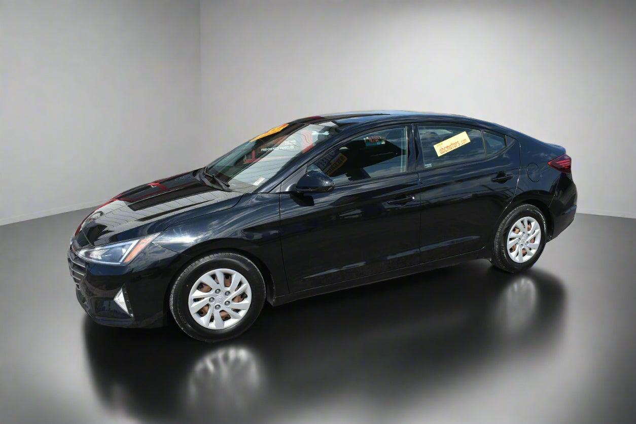 Black sedan car parked in front of a dealership building