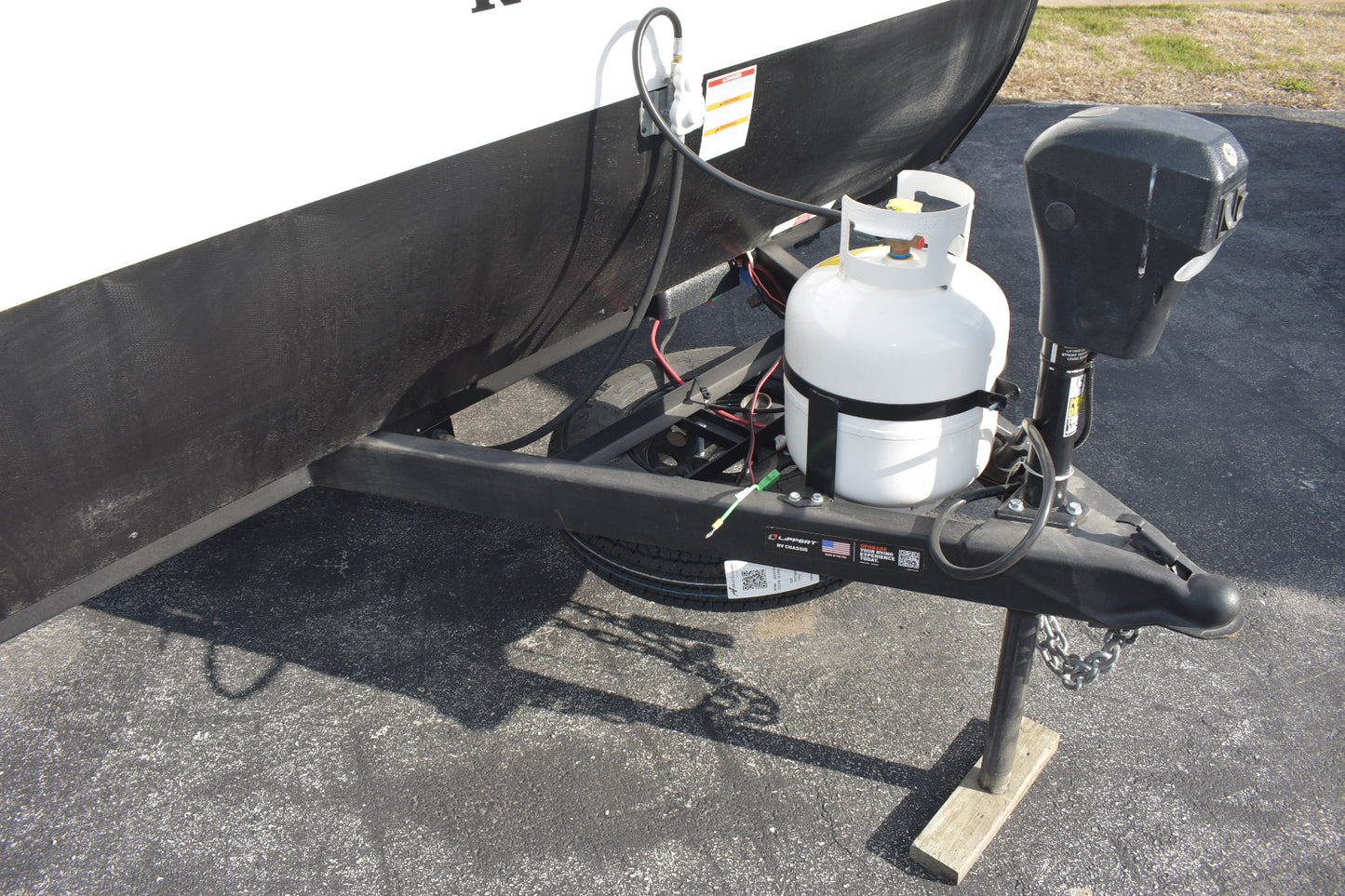 Black boat trailer with a propane tank attached on a paved surface