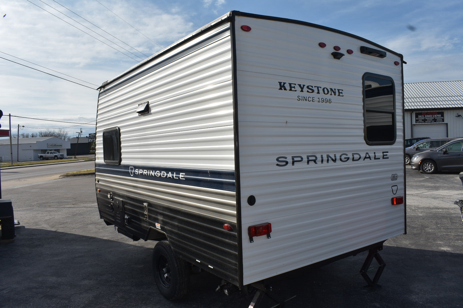 Keystone Springdale travel trailer parked on a lot with a clear sky.