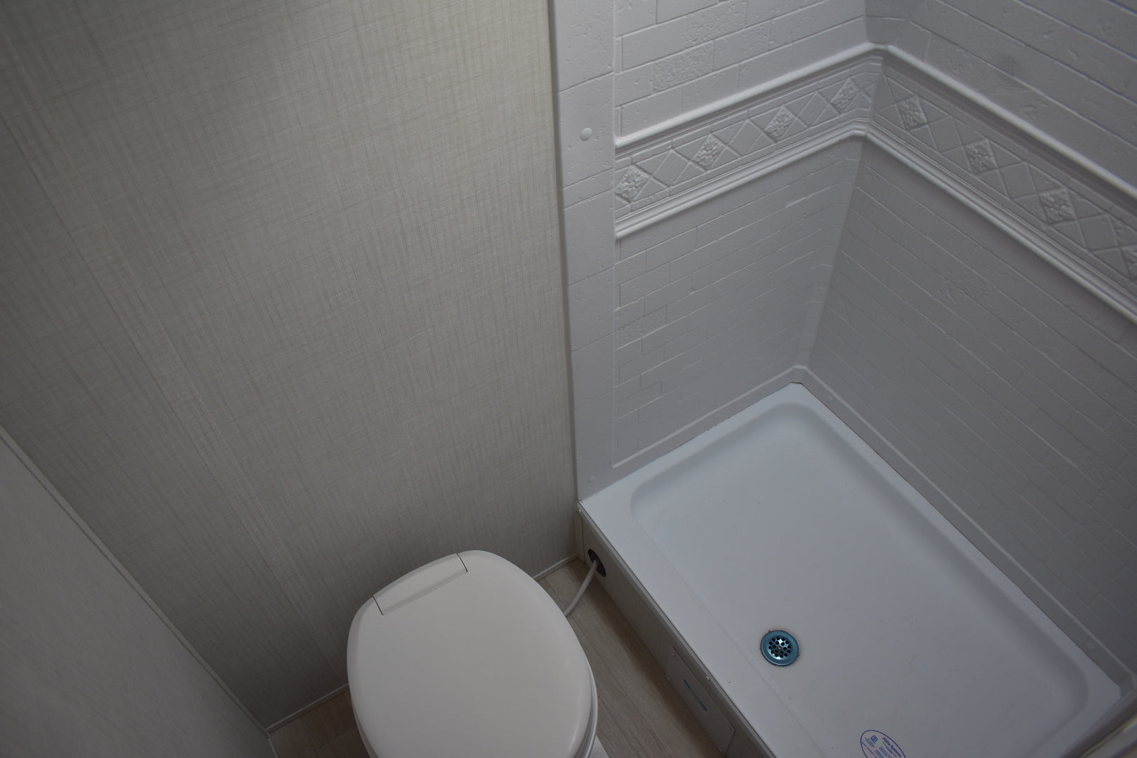 Small bathroom with a toilet and shower corner.
