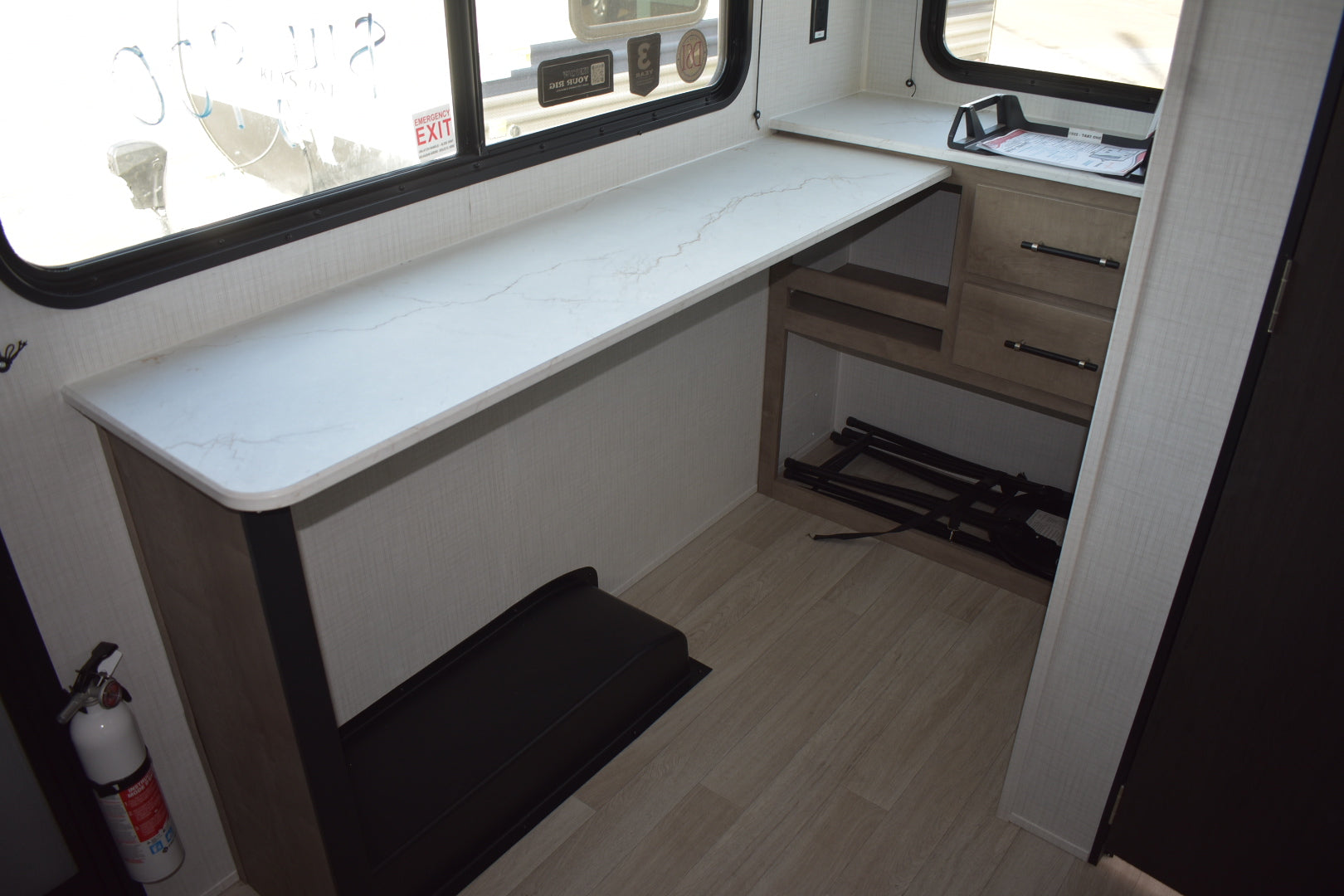 Interior of a vehicle with a white countertop and wooden cabinets.