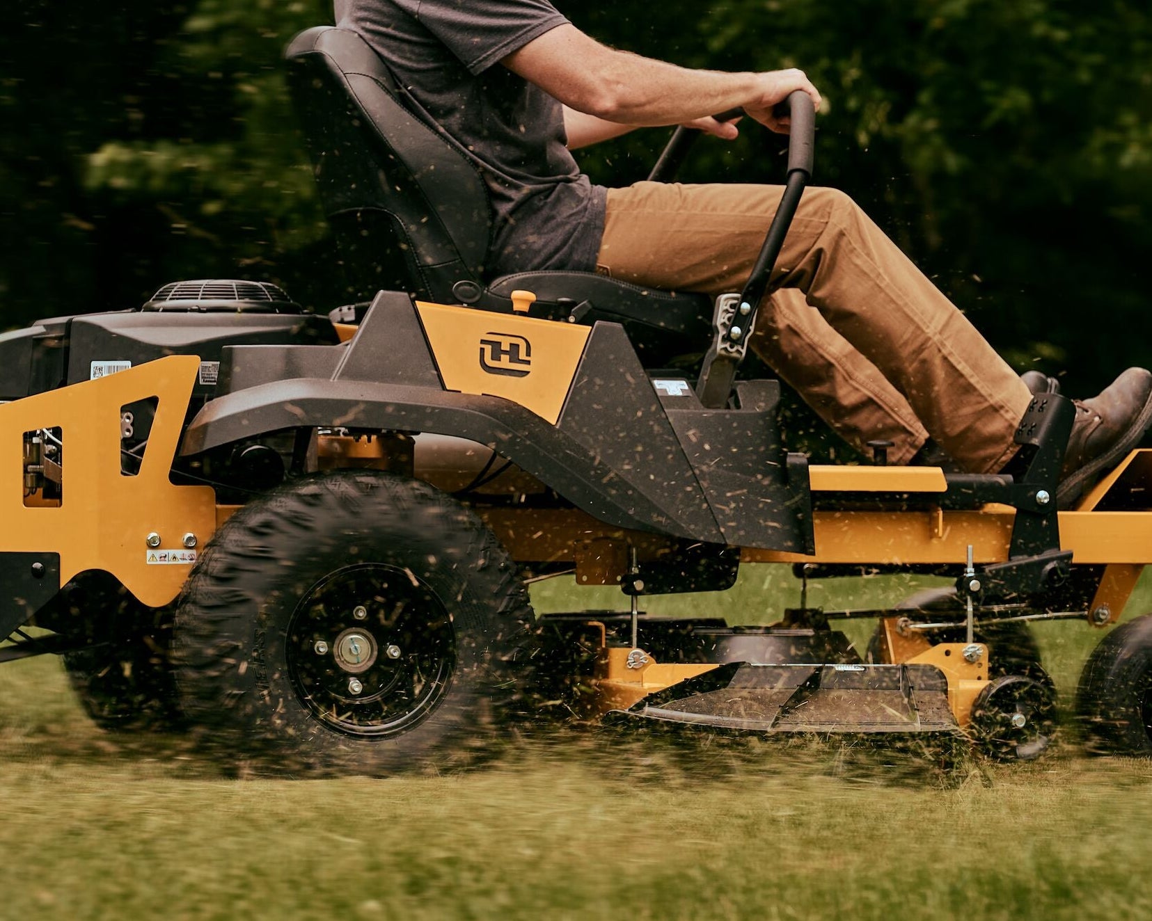 Person operating a large yellow lawn mower on grass