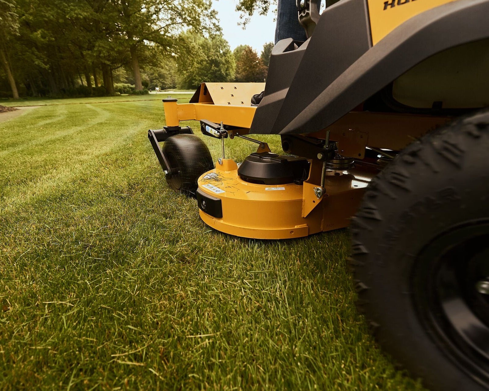 Mower cutting grass with a focus on the blade and wheels