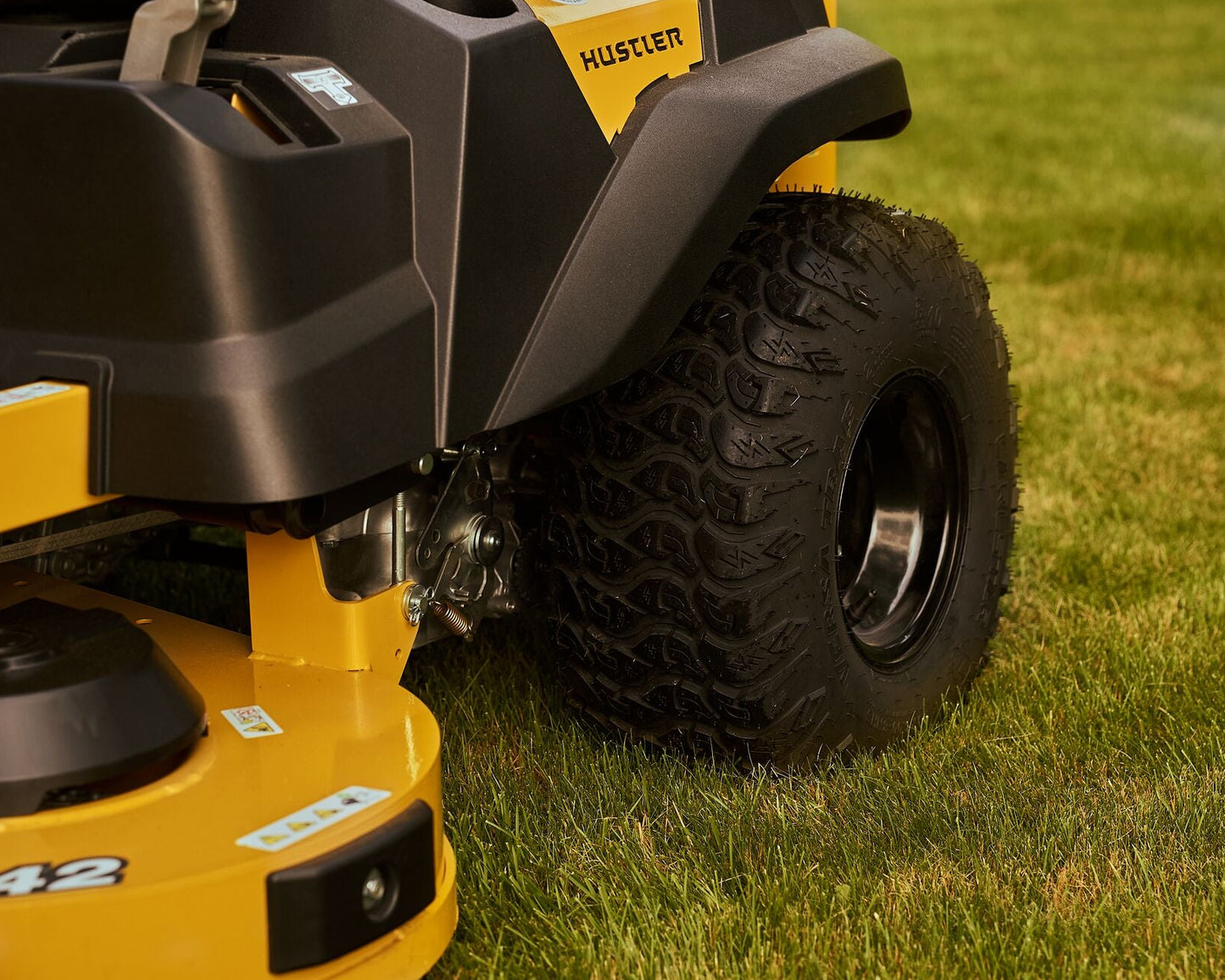 Close-up of a yellow and black Hustler lawn mower on grass