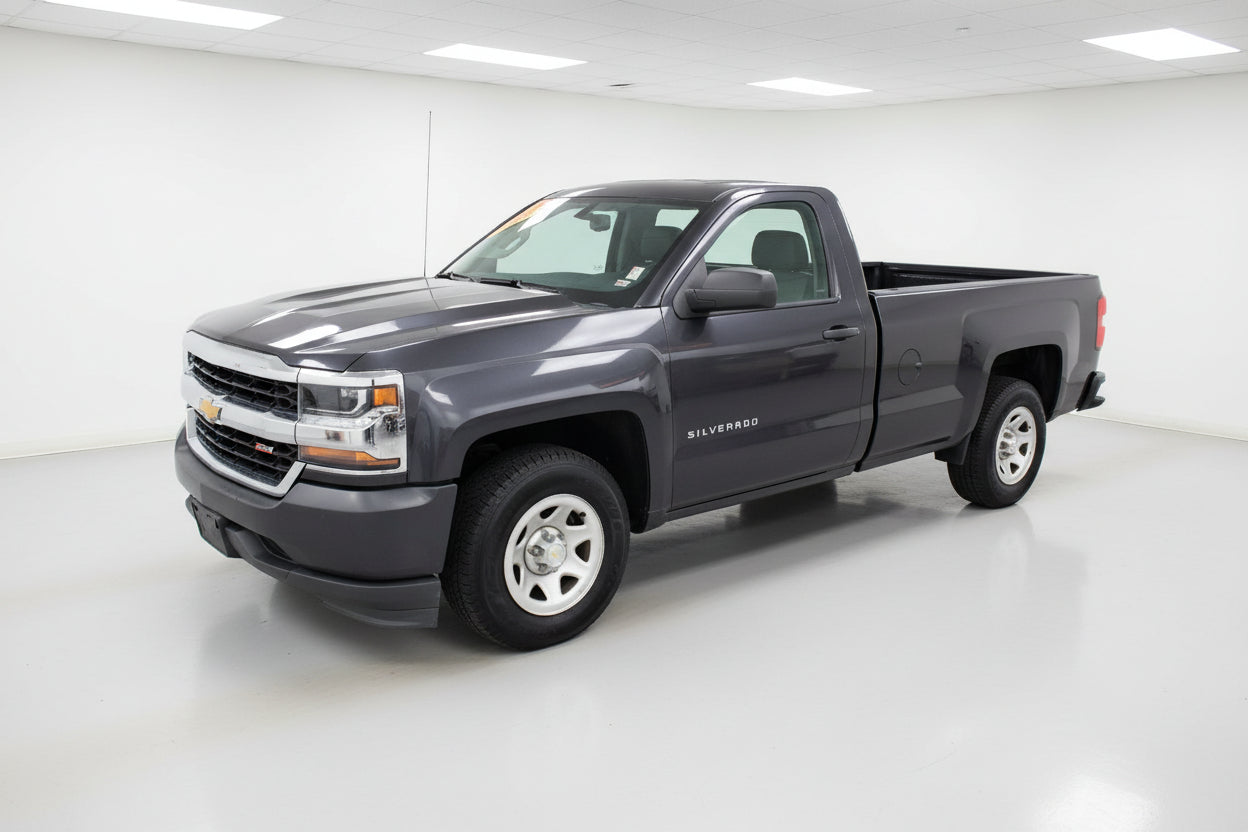 Gray Chevrolet Silverado truck parked in front of a building with red accents.