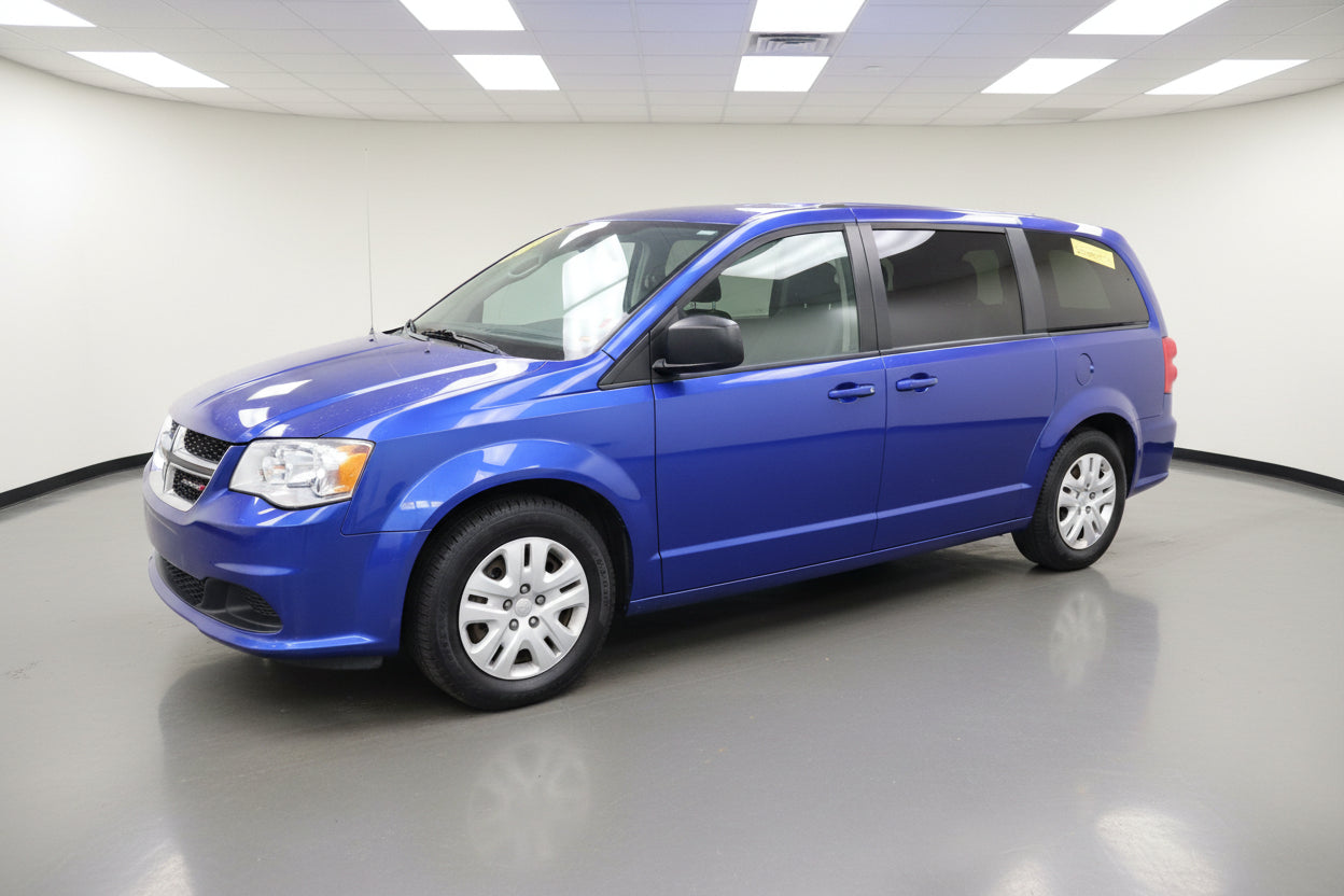 Blue minivan parked in front of a building with red doors.