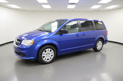 Blue minivan parked in front of a building with red doors.